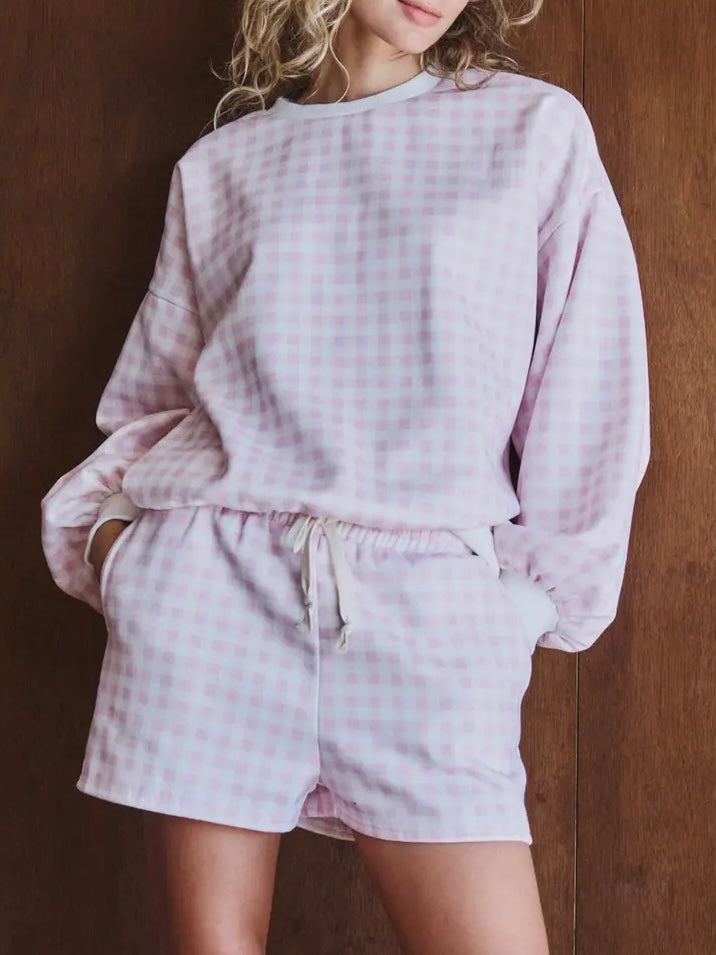 Person wearing a light purple checkered outfit against a wooden background