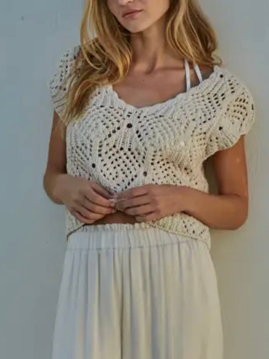 Woman wearing a white crochet top and skirt against a plain background