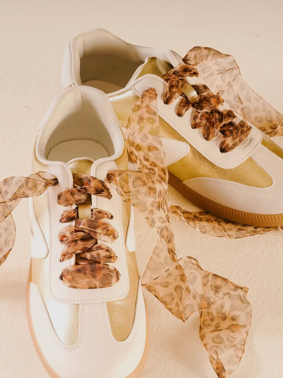 White sneakers with brown laces on a beige background