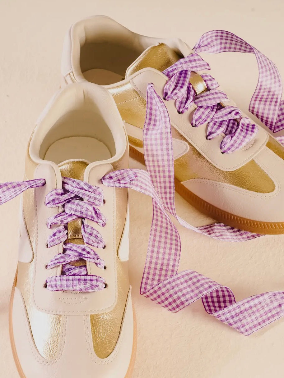 Beige sneakers with purple gingham laces on a beige background