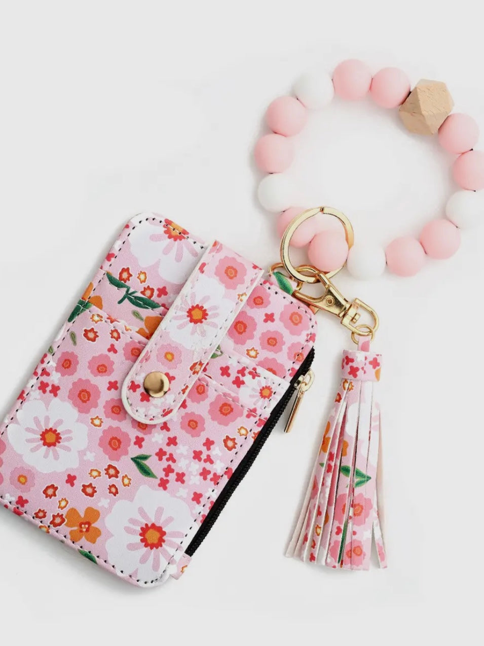 Floral keychain pouch with tassel and pink beaded bracelet on a white background