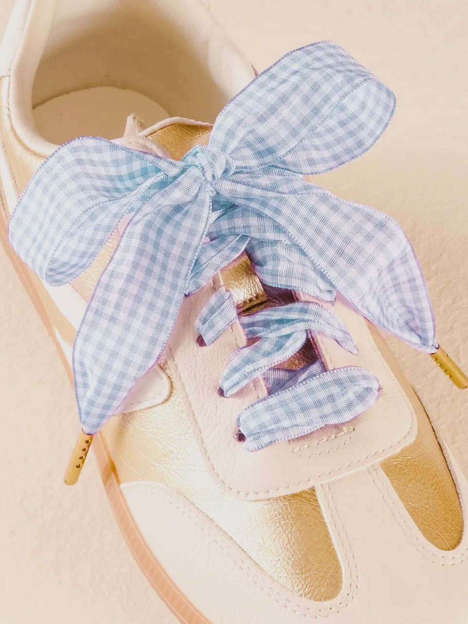 Beige sandal with a blue gingham bow on a beige background