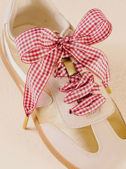 White sandal with a red and white checkered bow and scrunchies on a beige background