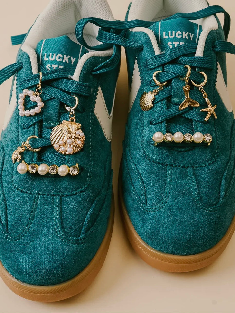 Teal sneakers with various charms on a beige background