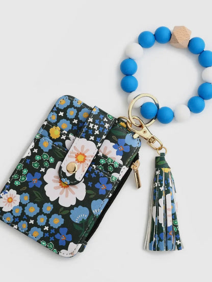Floral-patterned wallet with tassel and blue beaded keychain on a white background