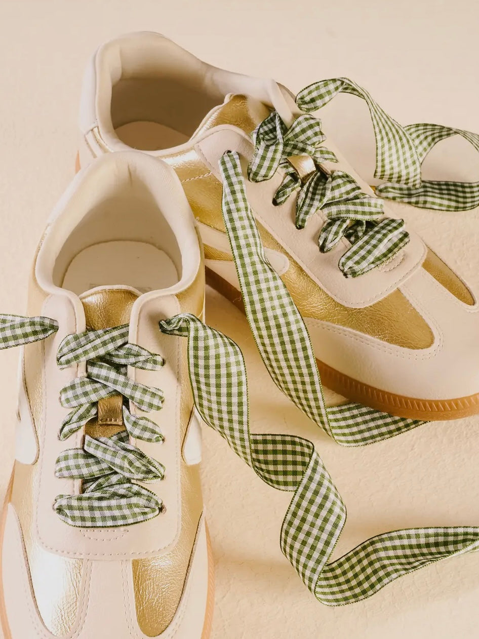 White sneakers with green gingham ribbons on a beige background