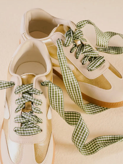 White sneakers with green gingham ribbons on a beige background