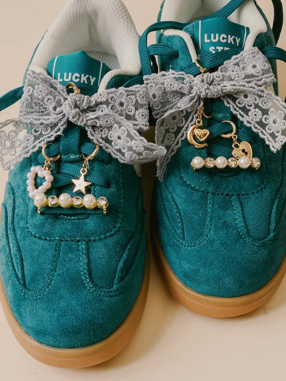 Teal sneakers with lace and charms on a beige background