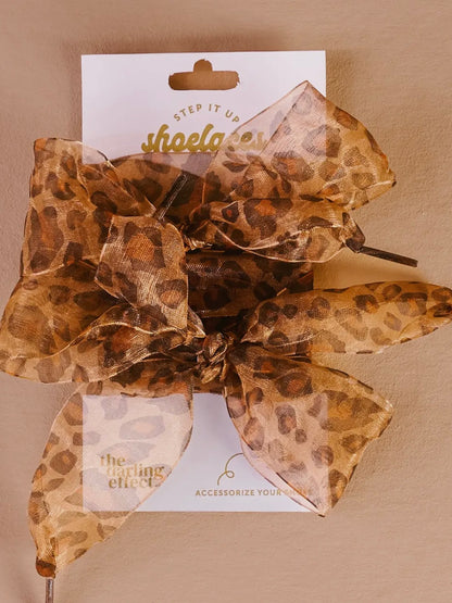 Leopard print hair bow on a beige background with 'Step It Up' branding.