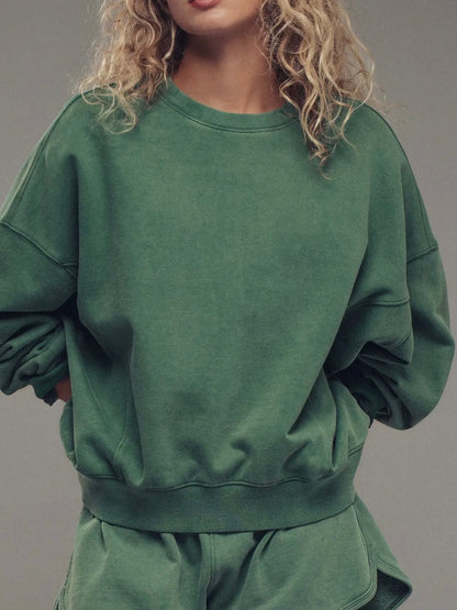 Person wearing a green sweatshirt and shorts set against a gray background