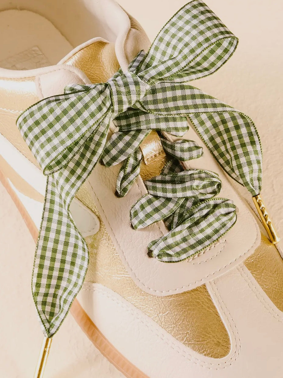 Close-up of a sandal with green and white checkered ribbons on a beige background
