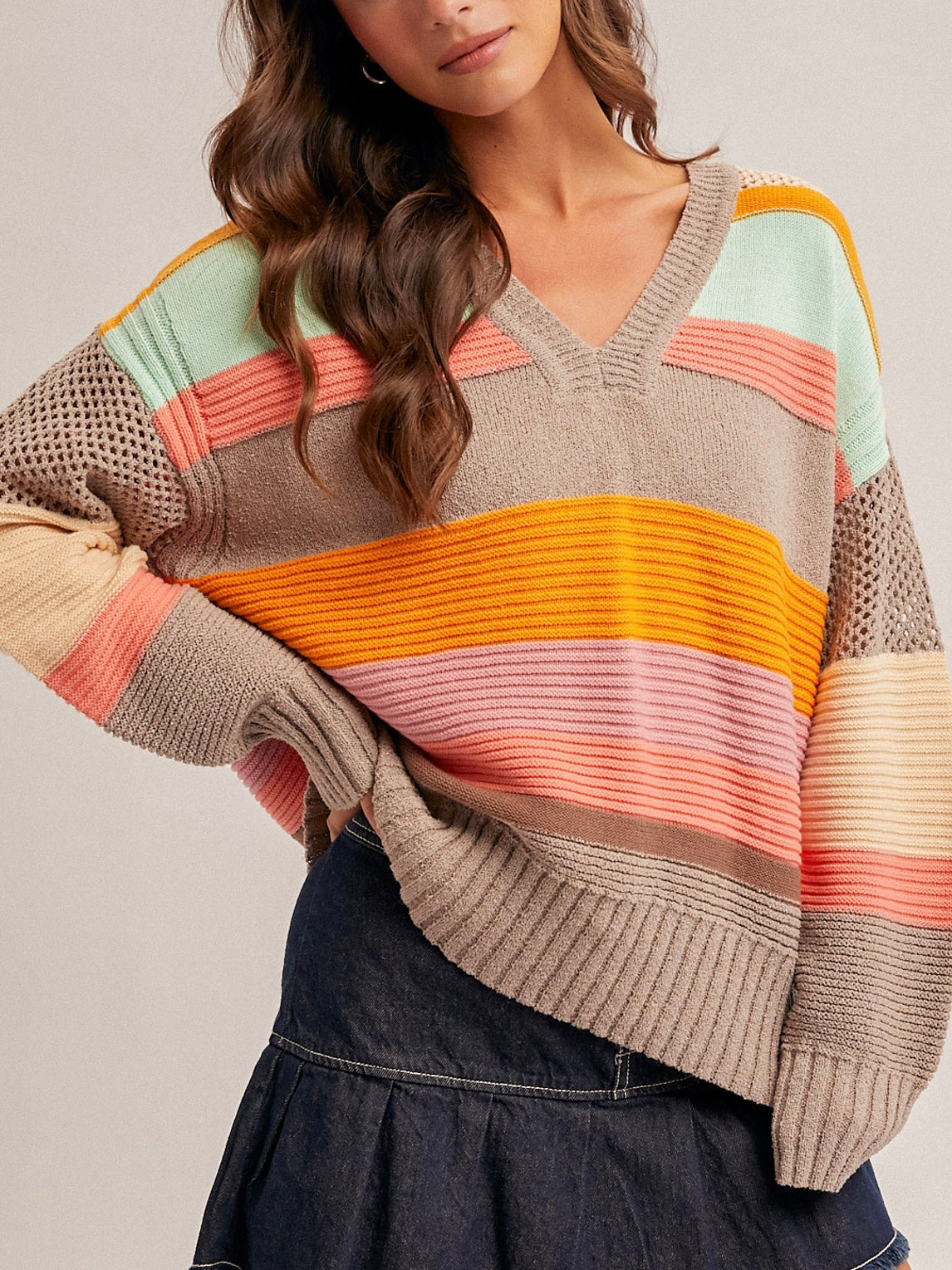 Colorful striped sweater worn by a person on a plain background
