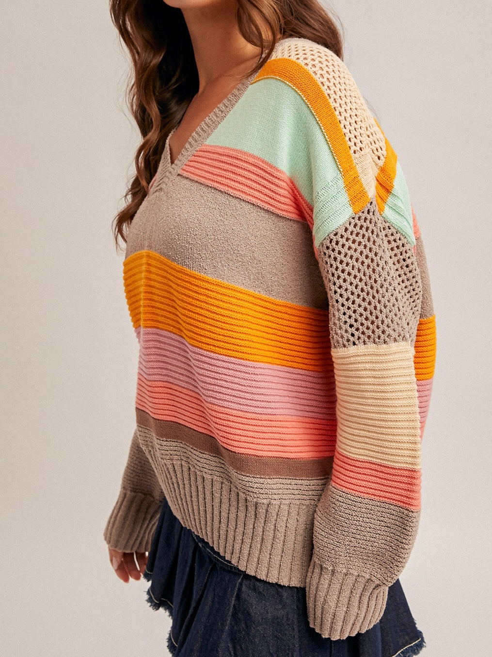 Colorful striped sweater worn by a person on a plain background