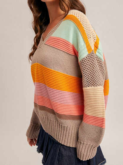 Colorful striped sweater worn by a person on a plain background