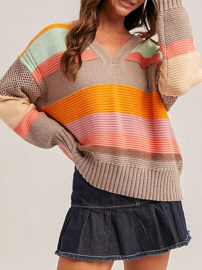 Person wearing a colorful striped sweater and denim skirt on a plain background