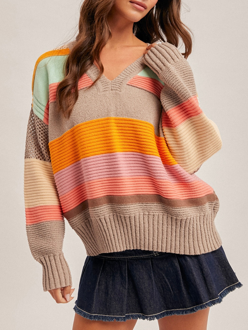 Person wearing a colorful striped sweater with a plain background