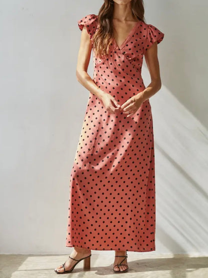 Woman wearing a pink polka dot dress against a neutral background