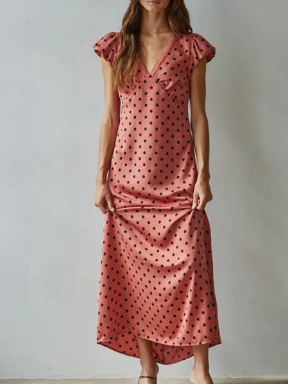 Woman wearing a pink polka dot dress against a plain background