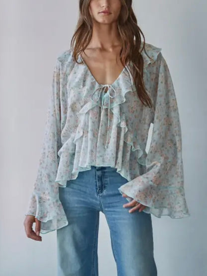 Woman wearing a floral blouse and blue jeans against a plain background