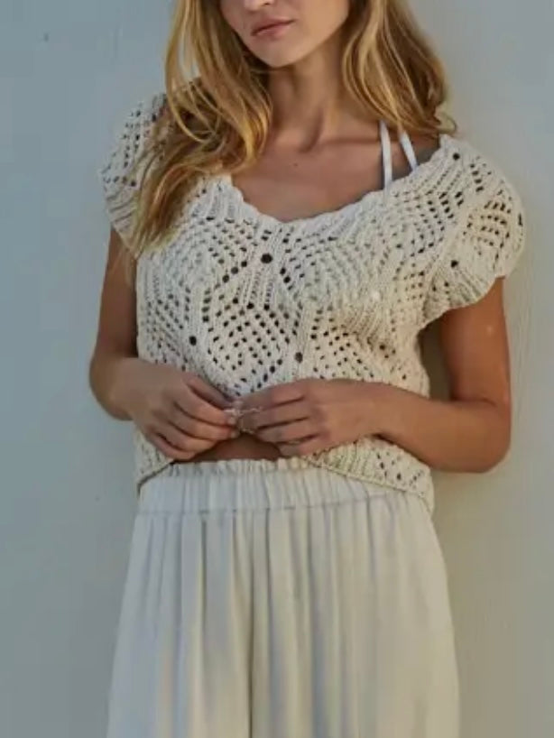 Woman wearing a white crochet top and skirt against a plain background