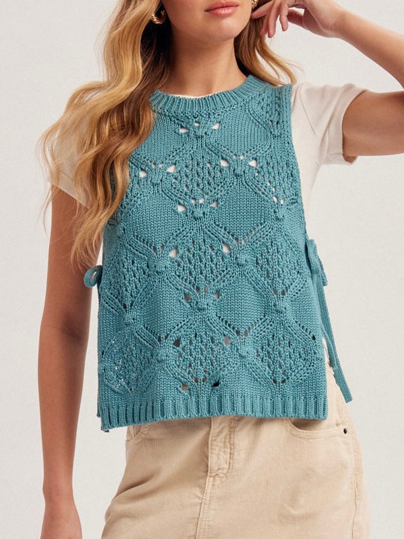 Woman wearing a blue knitted vest with a white background
