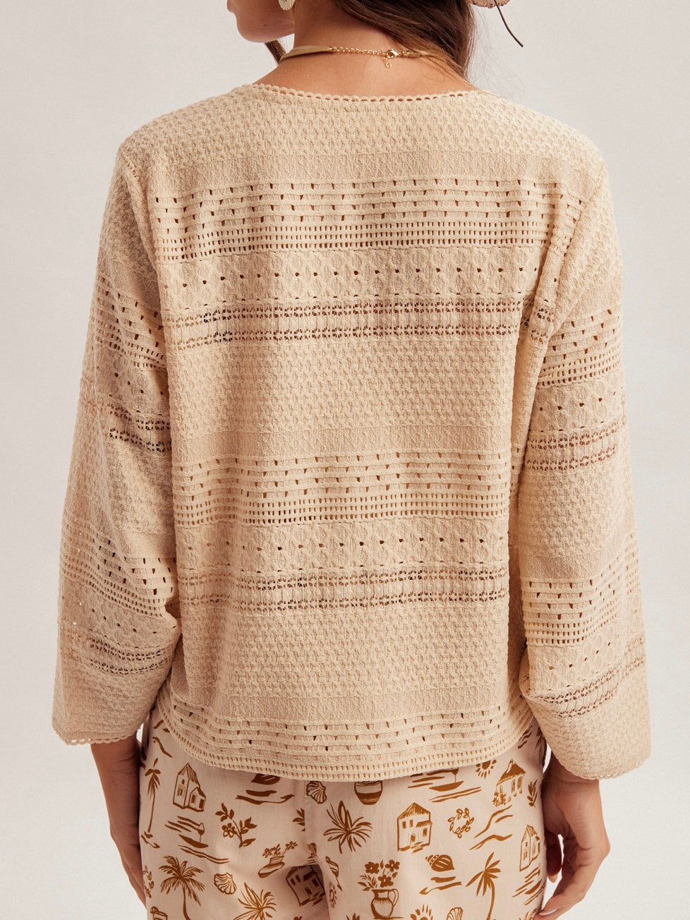 Beige crochet cardigan worn by a person on a plain background