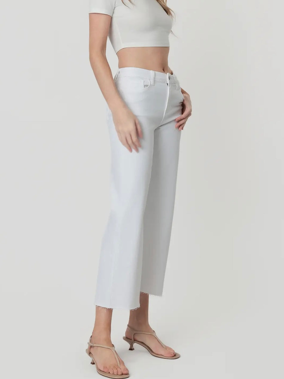 Person wearing white high-waisted jeans and a white top on a plain background
