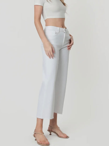 Person wearing white high-waisted jeans and a white top on a plain background