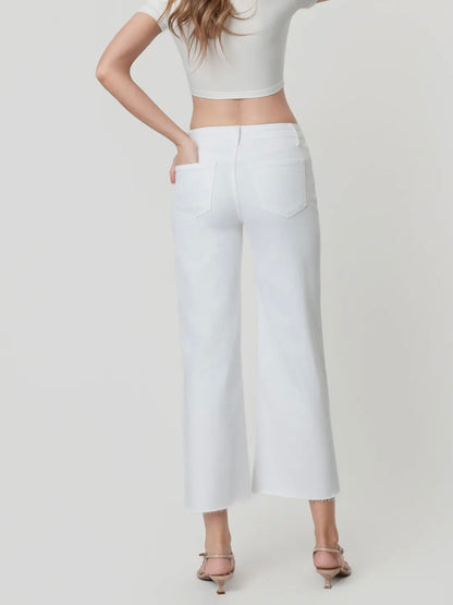 Person wearing a white crop top and white pants on a plain background