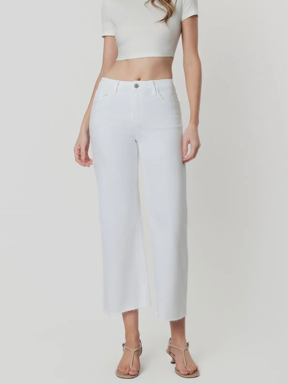 Person wearing a white crop top and white pants on a plain background
