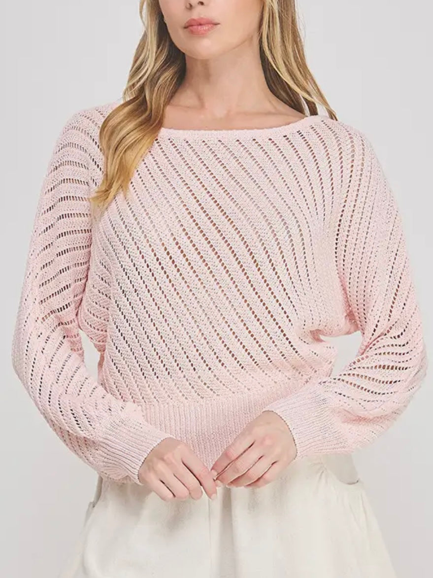 Woman wearing a light pink knitted sweater against a white background