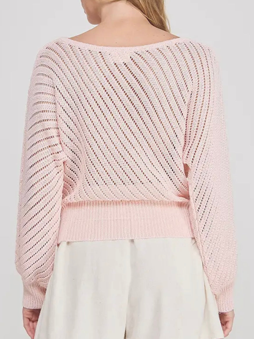 Light pink knitted sweater worn by a person on a white background
