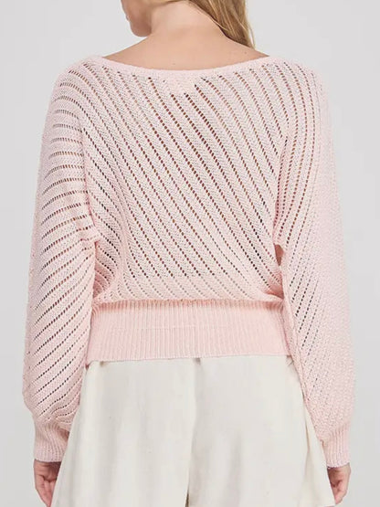 Light pink knitted sweater worn by a person on a white background