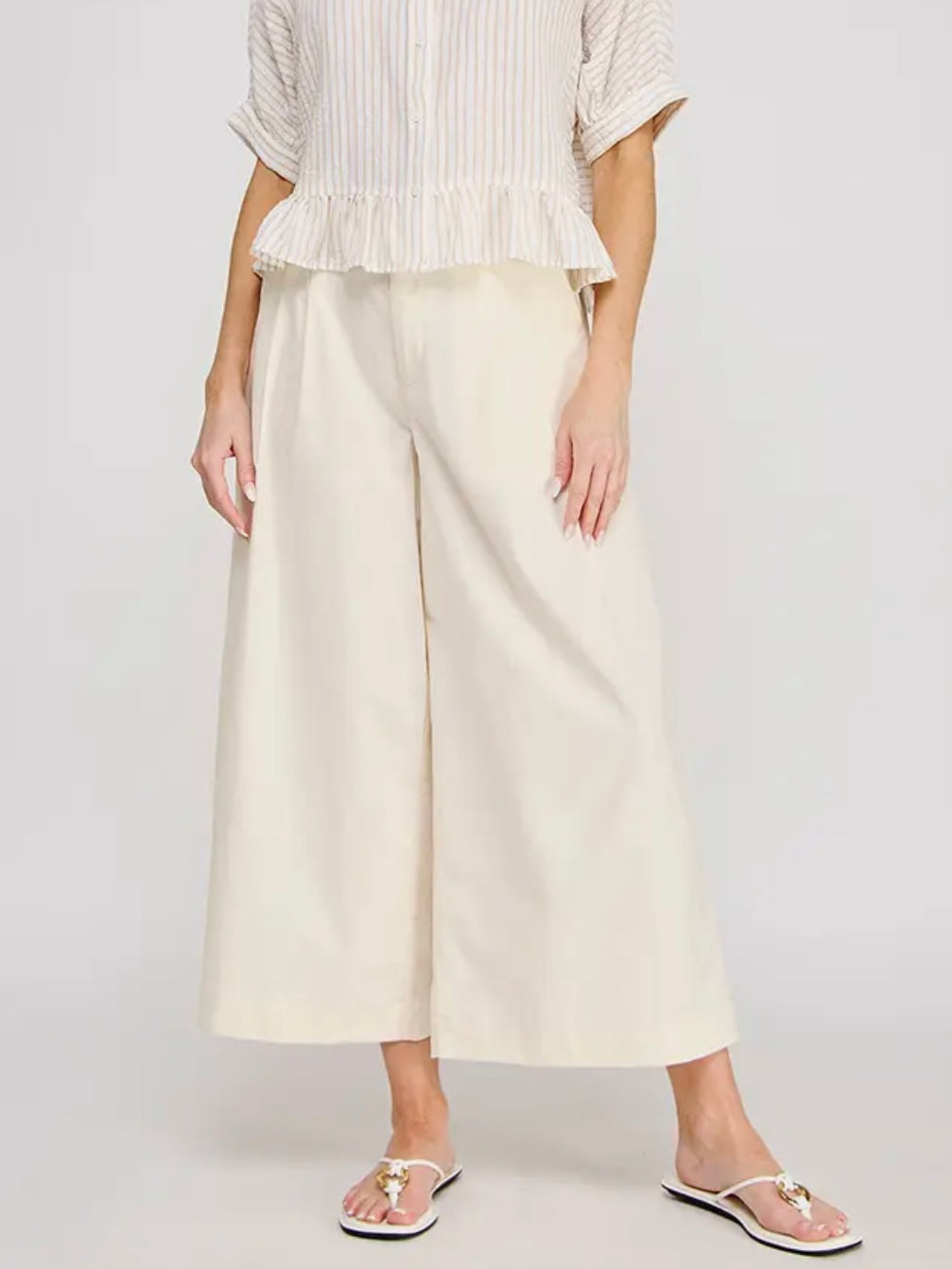 Person wearing a white top and wide-leg pants on a plain background