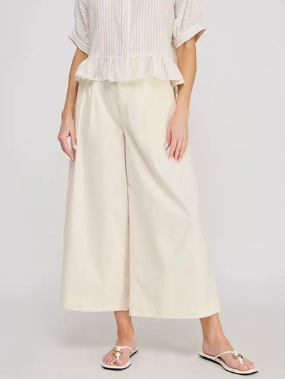 Person wearing a white top and wide-leg pants on a plain background