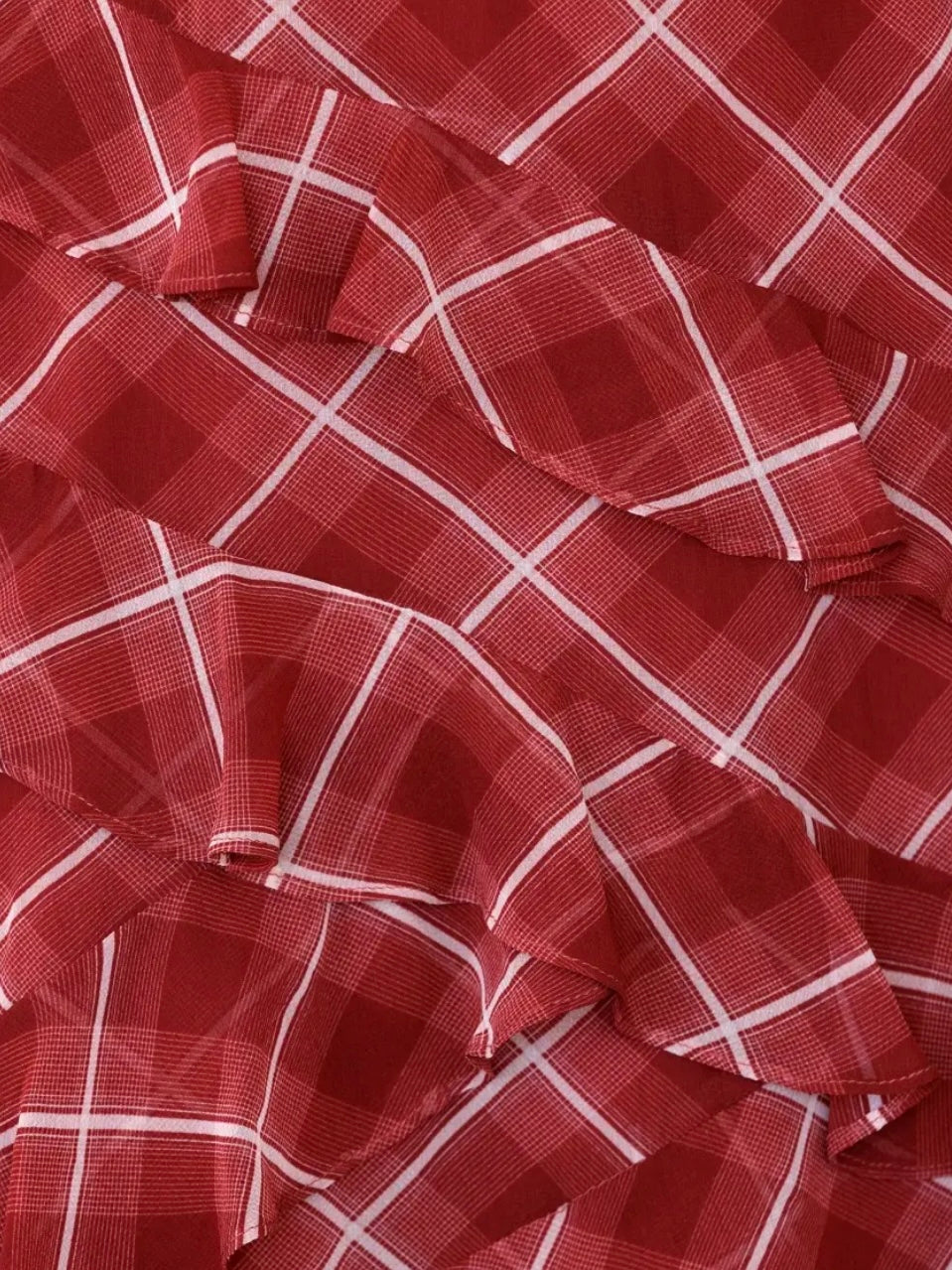Red and white plaid ruffled fabric closeup showing the texture and pattern.
