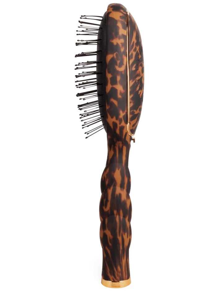 A hairbrush with a glossy tortoiseshell pattern handle and black bristles, shown against a plain white background.