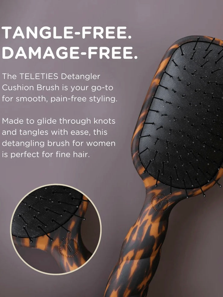 A hair detangling brush with a tortoiseshell-patterned handle and black cushioned bristle head, shown on a dark mauve background with promotional text and a circular detail inset.