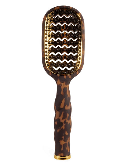 A hairbrush with a tortoiseshell pattern handle and head, featuring gold metal bristles and a gold accent at the base, shown against a plain white background.