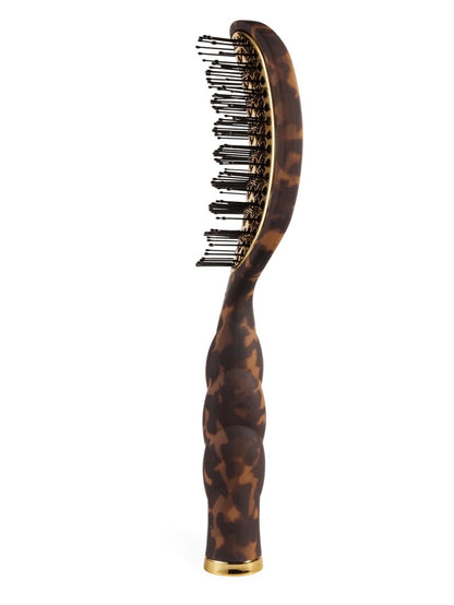 A curved hairbrush with a glossy tortoiseshell handle and head, black bristles, and gold-tone metal accents, shown against a plain white background.