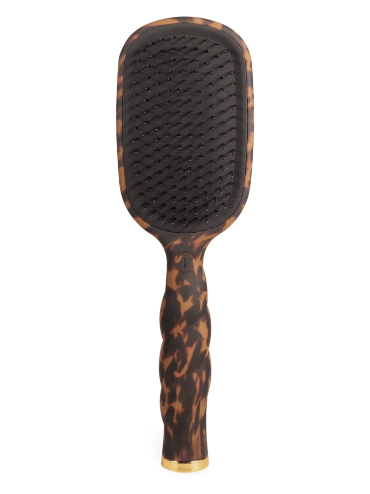 A paddle hairbrush with a dark brown and black tortoiseshell pattern, featuring a black bristle pad and a gold accent at the base, shown against a plain white background.