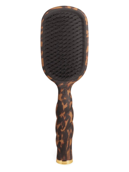 A paddle hairbrush with a dark brown and black tortoiseshell pattern, featuring a black bristle pad and a gold accent at the base, shown against a plain white background.