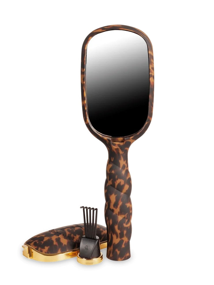 A handheld rectangular mirror with a brown and black leopard print handle, shown with its matching case and small black accessory on a plain white background.