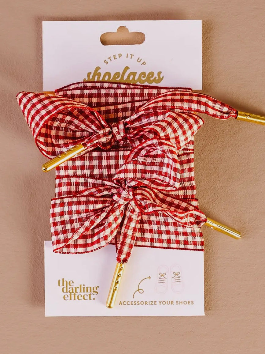 Red and white checkered shoelaces with gold accents on a beige background