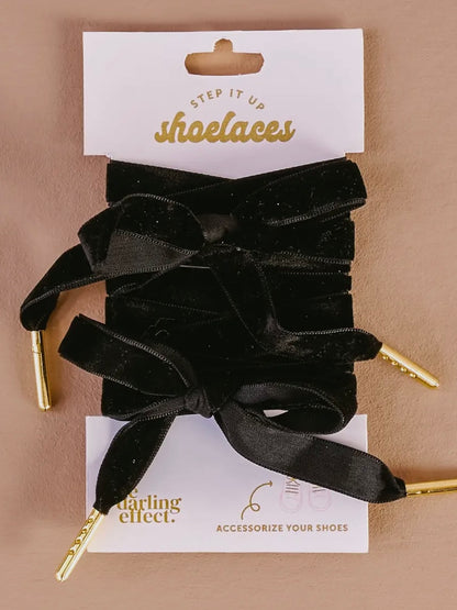 Black shoelaces with gold tips on a ' Darling Effect' card against a beige background