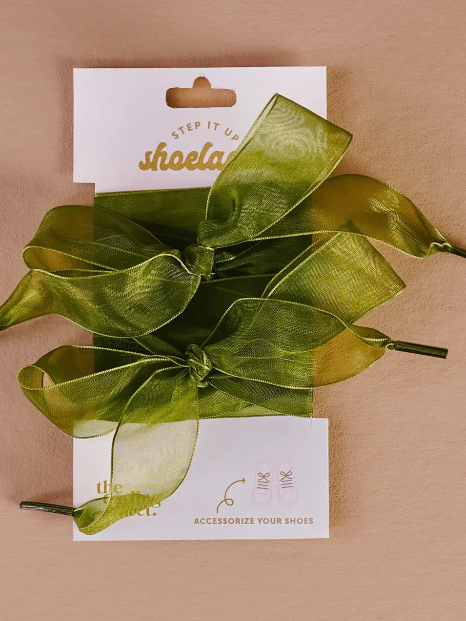 Green shoe lace with a white card displaying 'shela' branding on a beige background