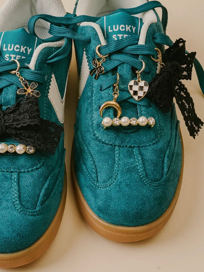 Teal sneakers with various charms on a beige background