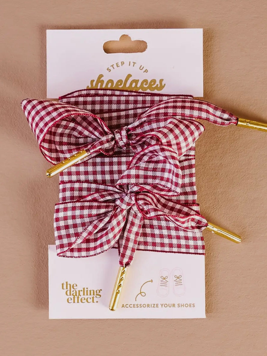 Red and white checkered shoelaces with a bow on a 'the darling effect' card against a beige background