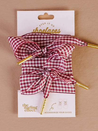 Red and white checkered shoelaces with a bow on a 'the darling effect' card against a beige background
