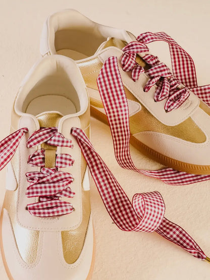 Beige sneakers with red and white checkered laces on a beige background